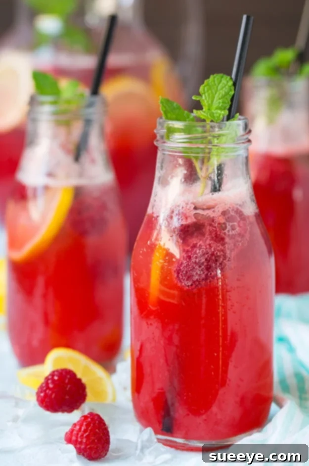 Zesty Sparkling Raspberry Lemonade: A Perfect Summer Sip Sparkling Raspberry Lemonade garnished with fresh raspberries and lemon slices, served in a mason jar.