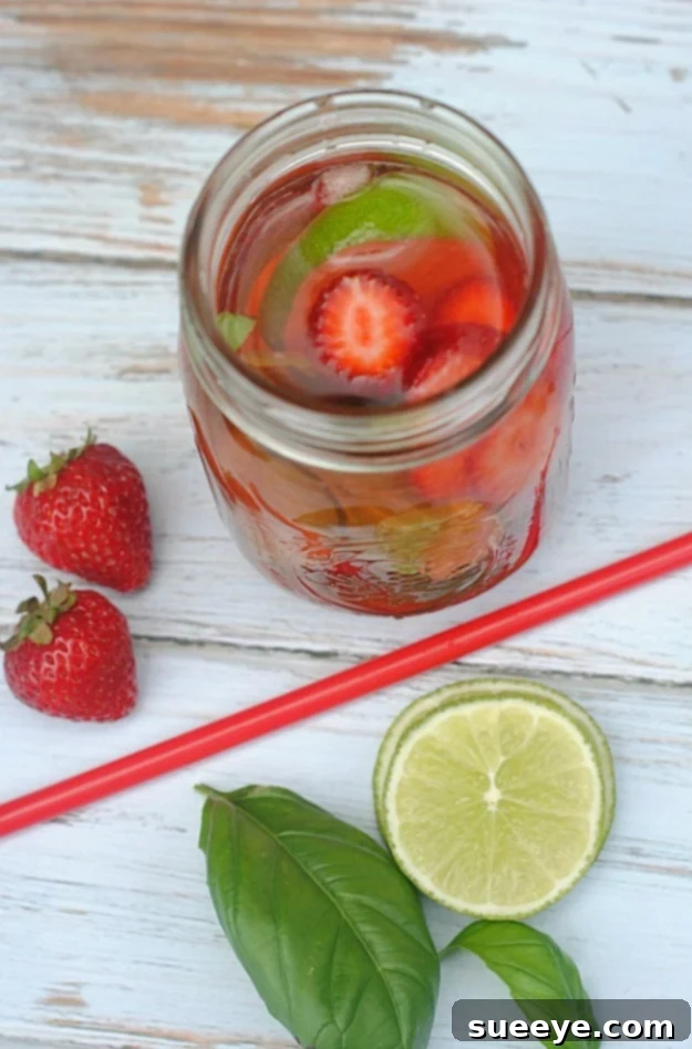 Detoxifying Strawberry Lime Basil Infused Water Refreshing Strawberry Lime Basil Infused Water in a clear pitcher with fresh ingredients.