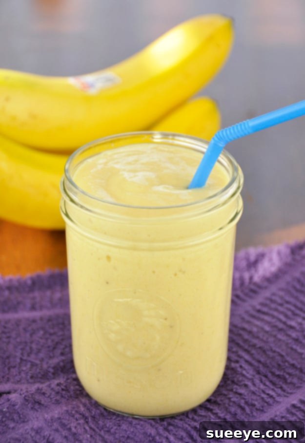 Sweet Banana Mango Smoothie: A Tropical Delight Creamy Banana Mango Smoothie in a glass with a straw, garnished with mango cubes.