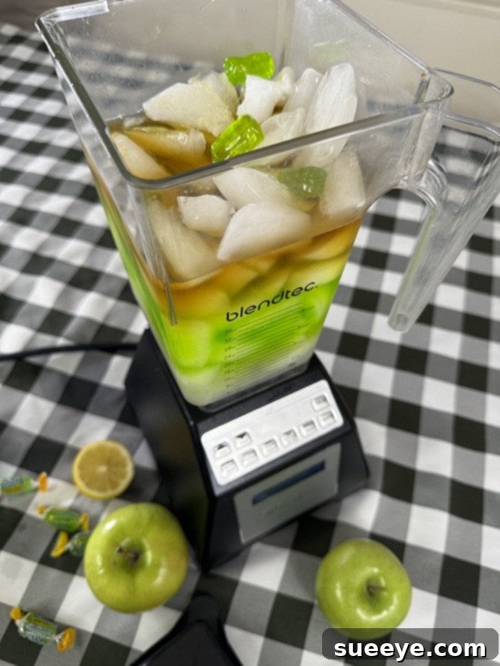Rancher's Crown Royal Apple Slush 9 Close-up of the inside of a blender with liquid ingredients and Jolly Ranchers, ready for ice