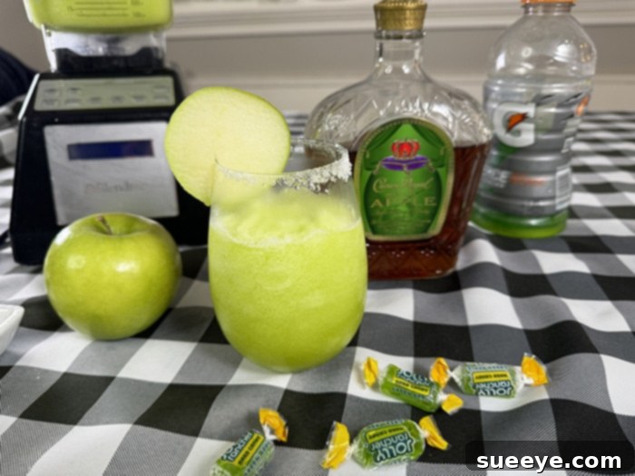 Rancher's Crown Royal Apple Slush 15 A freshly poured Crown Royal Apple Jolly Rancher slushie in a sugar-rimmed glass with apple garnish