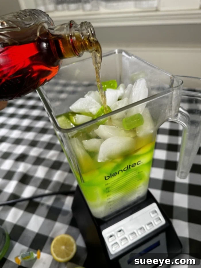 Rancher's Crown Royal Apple Slush 2 Vibrant green Crown Royal Apple slushie in a stemmed glass with apple garnish on a wooden table