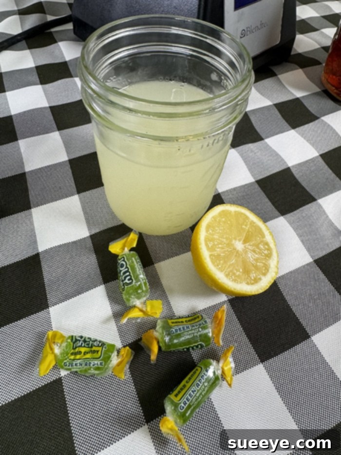 Rancher's Crown Royal Apple Slush 4 All ingredients for Crown Royal Apple slushie, including whisky, Gatorade, lemonade, and Jolly Ranchers, laid out on a table