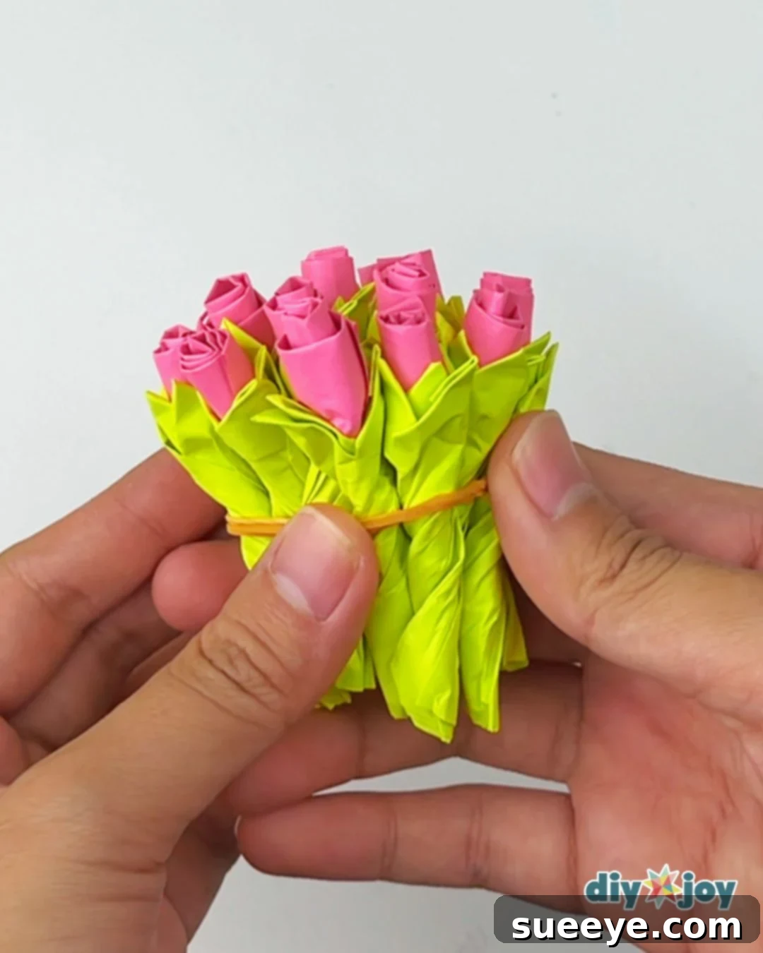 Arranging multiple sticky note paper flowers into a bouquet and securing them with a rubber band
