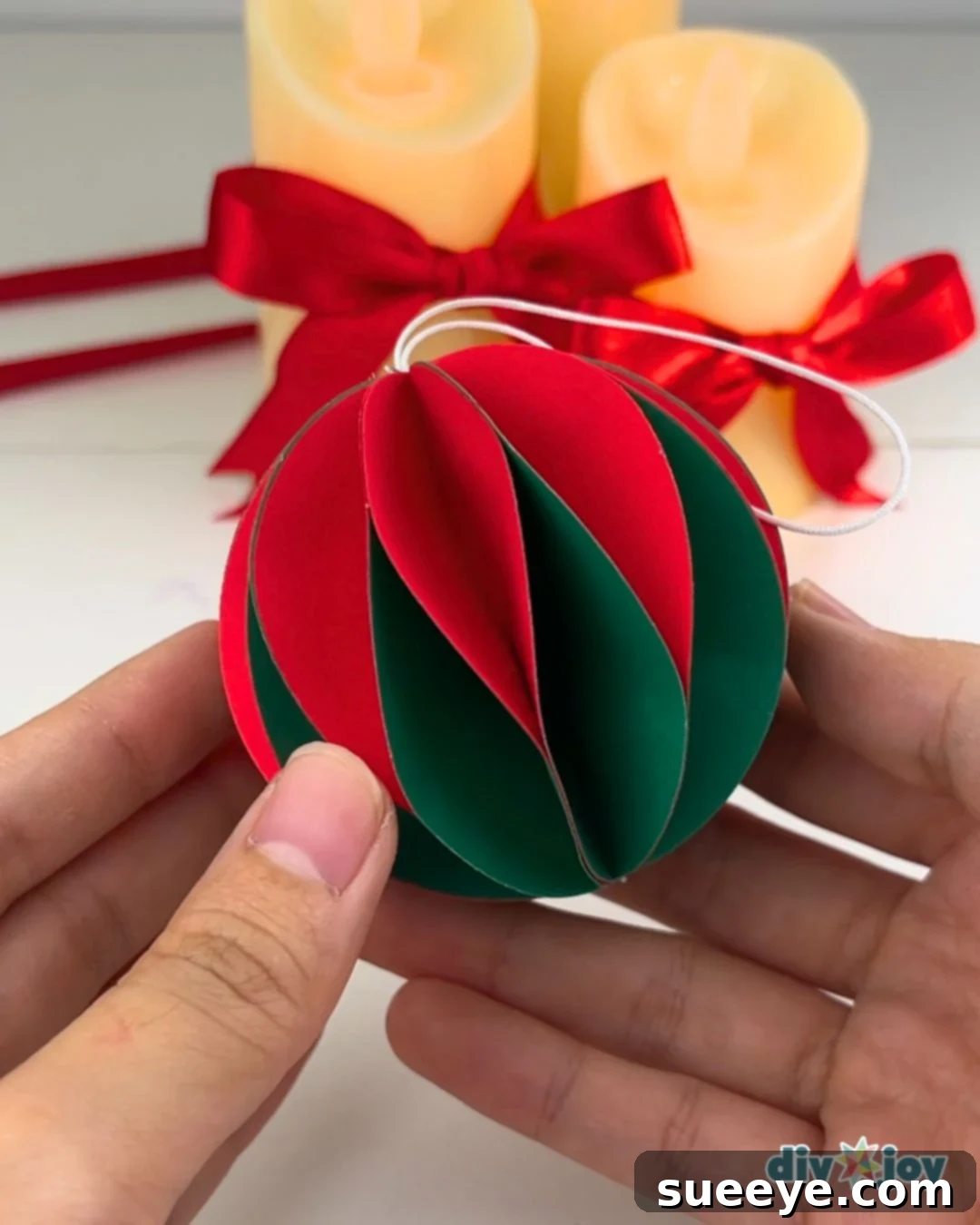 Make Easy Paper Christmas Ornaments 9 DIY Paper Ornaments - Attaching the string loop to the top of the ornament with hot glue.