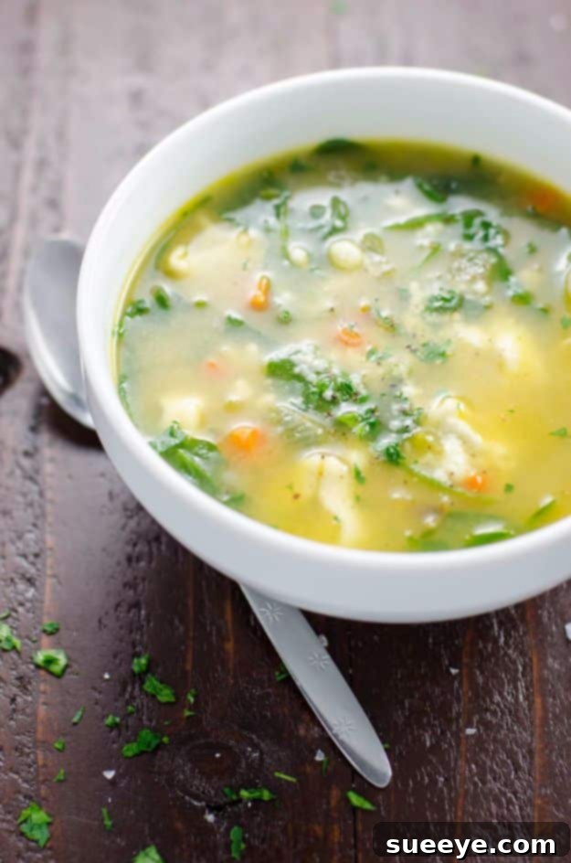 A bowl of hot Spinach Tortellini Soup with a spoon
