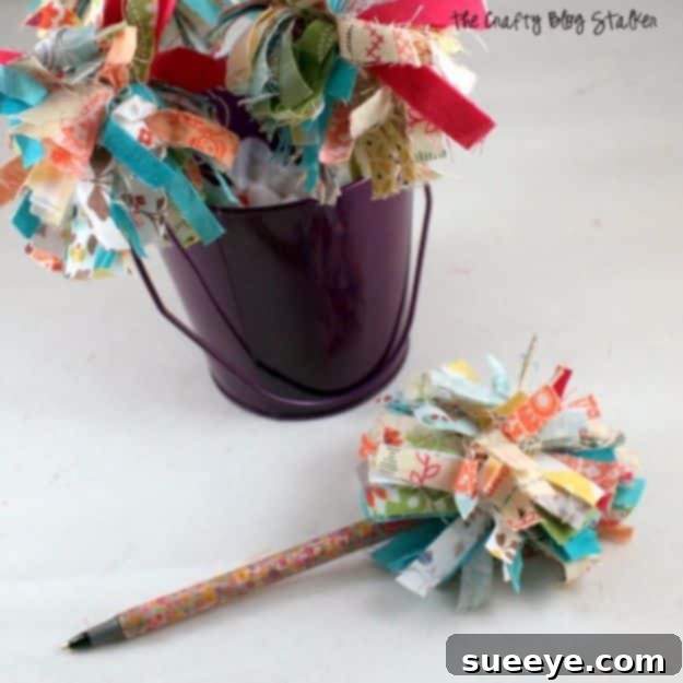 Pen embellished with a fluffy pom-pom made from colorful fabric scraps, for fun stationery.
