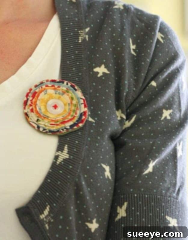 Decorative fabric brooch pinned to clothing, showcasing small fabric scraps and buttons.