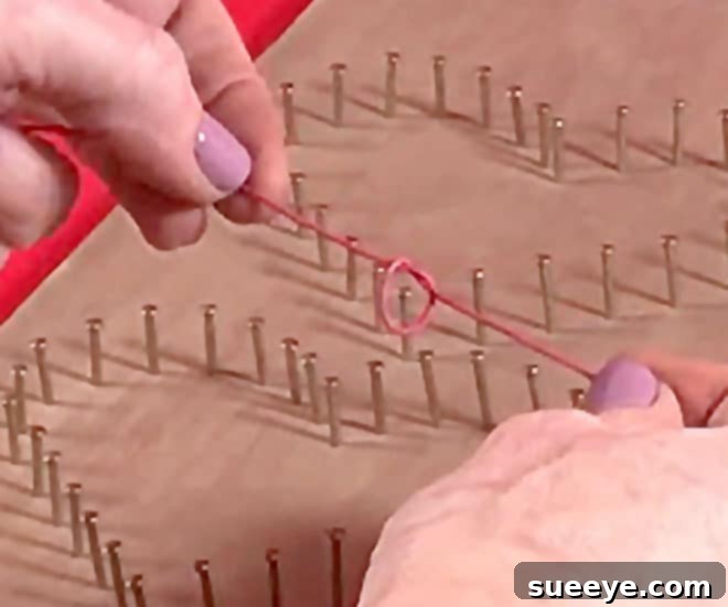 3 Beginner-Friendly String Art Projects 3 Hand holding small wire nails over a wooden surface