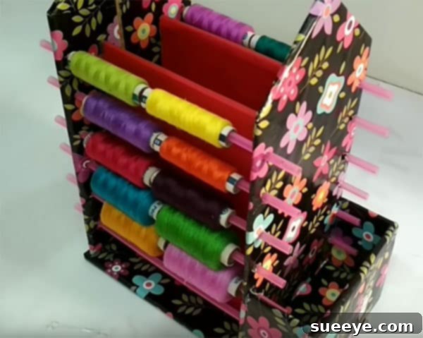 Close-up of DIY cardboard spool organizer showing plastic straws and spools