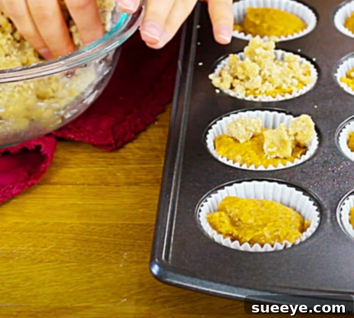 Sweet Glazed Pumpkin Streusel Muffins 3 Freshly baked streusel-topped pumpkin muffins cooling in a muffin tin