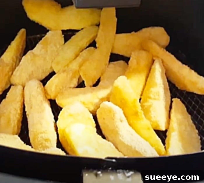 Crispy Air Fryer Apple Fries with Cream Cheese Dip 3 Golden-brown crispy apple fries cooking in an air fryer basket, showing the perfect texture.