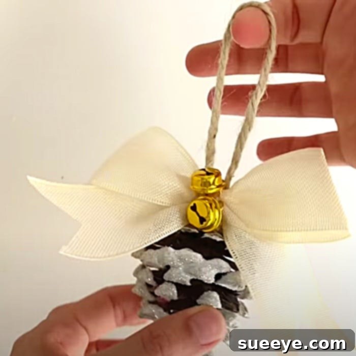 Frosted Forest Pinecone Ornaments 3 Finished DIY Flocked Pinecone Ornament with ribbon and bell, ready to hang on a Christmas tree. Perfect for rustic and handmade holiday decor.