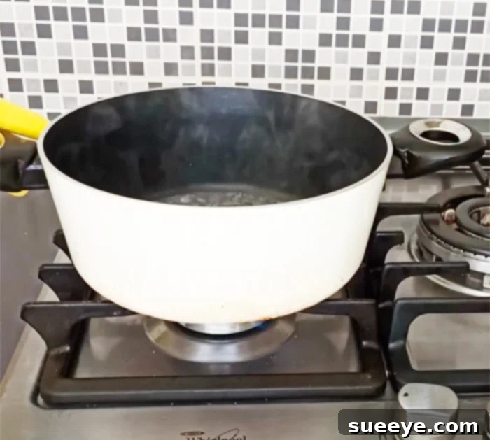 Effortlessly Clean Greasy Pots and Pans 2 Preparing a pot with water on the stove to heat for grease stain removal, an effective DIY cleaning tip for pots and pans.