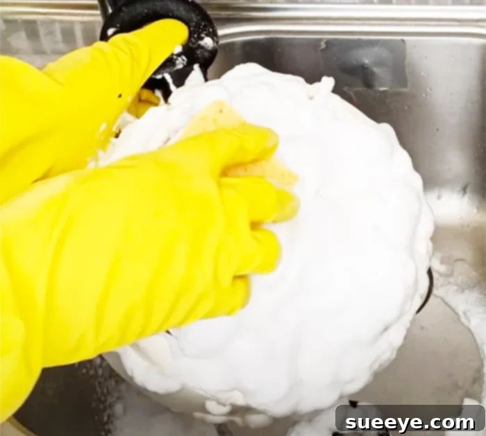 Effortlessly Clean Greasy Pots and Pans 3 Applying oven cleaner to the bottom of a pan to clean grease stains, a simple and inexpensive kitchen cleaning hack.