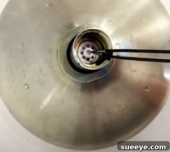 Boost Your Shower Pressure 3 Easy Ways To Fix Low Water Pressure - Low Water Pressure in Shower - Easy Fix Using Tweezers For Faster Water. A close-up image showing tweezers removing a black rubber ring from a shower head.