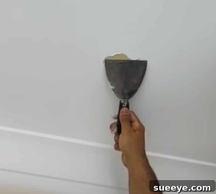 Fixing Peeling Flaking And Bubbling Paint 2 DIY Flaking Paint - How To Fix Peeling Paint- Ceiling Paint Peeling - A close-up view showing the initial scraping and sanding stages of fixing peeling ceiling paint, revealing a prepared patch.