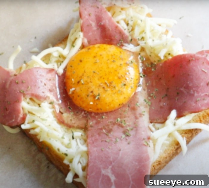 Air Fryer Loaded Breakfast Toast 3 Assembling air fryer cheese egg bacon toast with cheese, bacon, and egg on bread