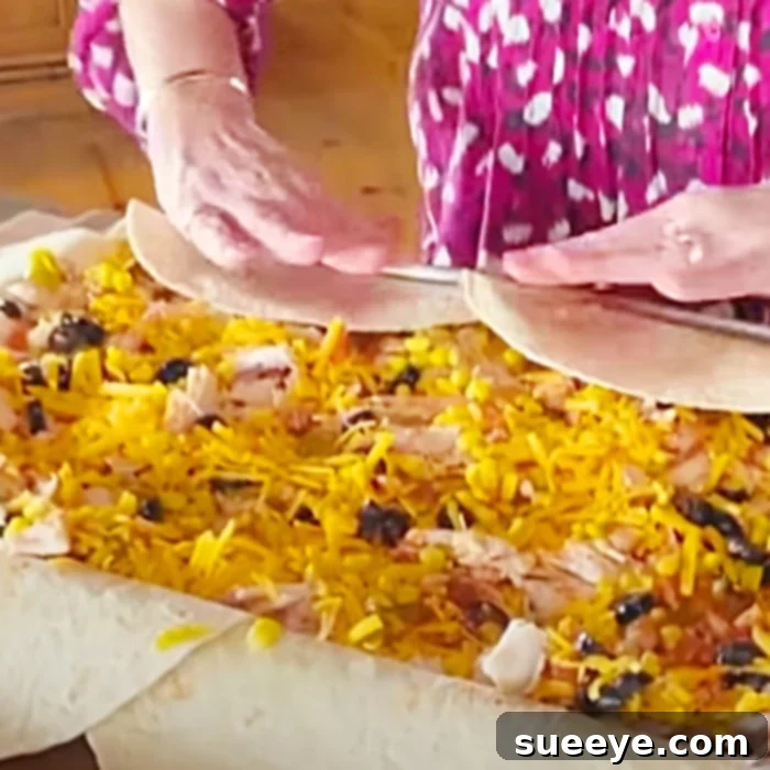 Sheet Pan Chicken Quesadillas Recipe - How To Make Quesadillas - Easy Dinner Ideas. Close-up of a sheet pan chicken quesadilla being sliced into wedges, showing the melted cheese and chicken filling.